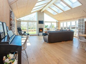 A spacious living area with a fireplace, a sofa, and a dining table. - 4 Star Holiday Home in Juelsminde (Horsens)