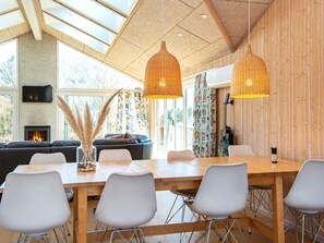 A modern dining area with a long wooden table, white chairs, and two wicker pendant lights. - 4 Star Holiday Home in Juelsminde (Horsens)
