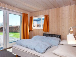 A bedroom with a bed, curtains, a window, and a lamp. - 4 Star Holiday Home in Juelsminde (Horsens)