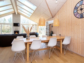 A modern dining area with a wooden table, white chairs, and a large wall clock. - 4 Star Holiday Home in Juelsminde (Horsens)
