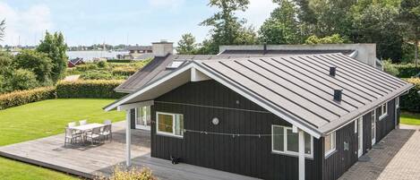 A modern house with a sloped roof, a deck, and a view of the water.