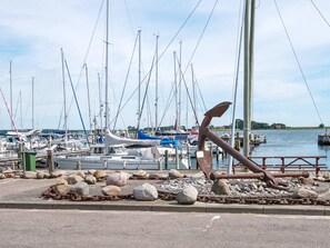 A marina with boats docked, a large anchor sculpture, and a calm water body. - 4 Star Holiday Home in Juelsminde (Horsens)