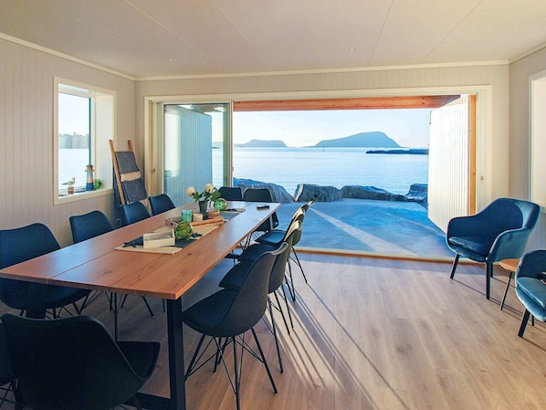 Ein Essbereich mit Meerblick, einem Holztisch und modernen Stühlen.
