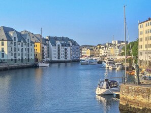 En hamn med byggnader längs vattnet, en båt förtöjd vid kajen och en klar himmel.