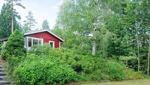 A red cabin surrounded by dense greenery and trees.