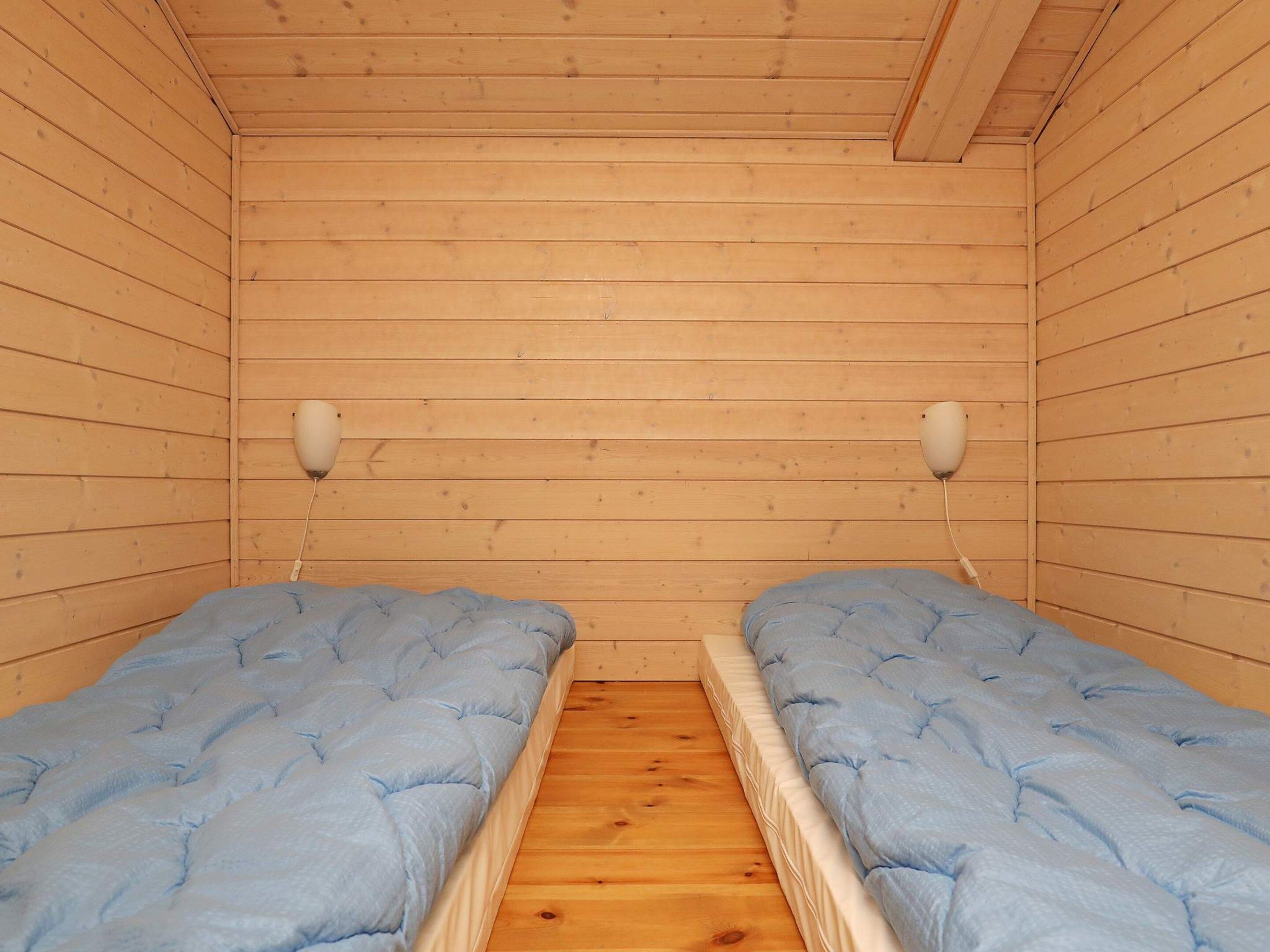 A cabin with two beds, wooden walls, and a wooden floor.
