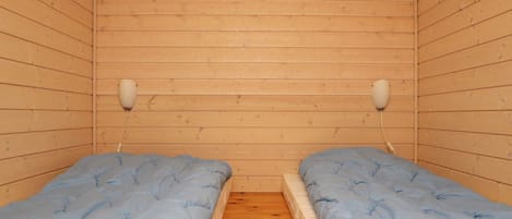 A cabin with two beds, wooden walls, and a wooden floor.