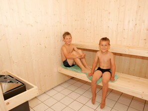 Two children sitting on wooden benches in a room with tiled flooring. - 5 Star Holiday Home in Vinderup (Vinderup)