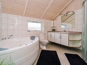 A modern bathroom with a freestanding bathtub, a toilet, and a vanity with a mirror.