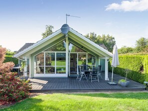 Une maison moderne dotée d’un patio couvert, d’une antenne parabolique et d’un jardin bien entretenu.