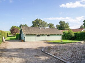 A single-story building with a sloped roof, surrounded by a gravel driveway and a well-maintained lawn. - 4 Star Holiday Home in Gorlev (Gørlev)