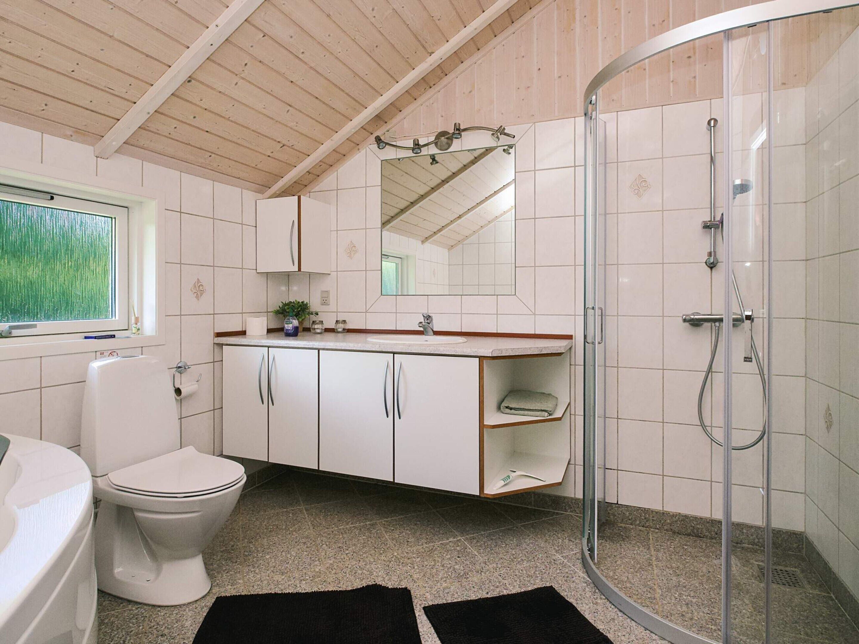Ein Badezimmer mit Toilette, Waschbecken, Spiegel und Dusche.