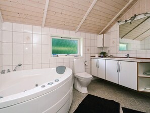 Une salle de bain avec une baignoire, des toilettes et une fenêtre donnant sur une pelouse.