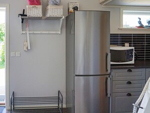 A kitchen with a stainless steel refrigerator, a microwave, and a drying rack. - 4 Star Holiday Home in Okero (Öckerö)