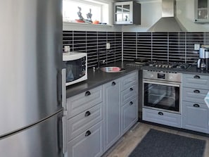 A kitchen with grey cabinets, a stainless steel refrigerator, a microwave, a stove, and a sink. - 4 Star Holiday Home in Okero (Öckerö)