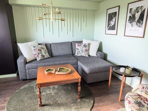 A modern living room with a grey sectional sofa, a wooden coffee table, a small side table, and a round rug.