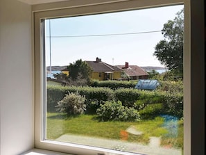 Uitzicht vanuit een raam op een woonwijk met huizen, groen en een heldere lucht.