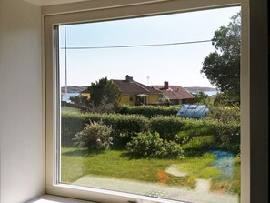 A window with a view of a house, a greenhouse, and a grassy area.