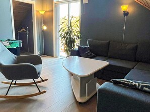 A modern living room with a sofa, a rocking chair, a coffee table, and a plant. - Holiday Home in Auklandshamn (Sveio)