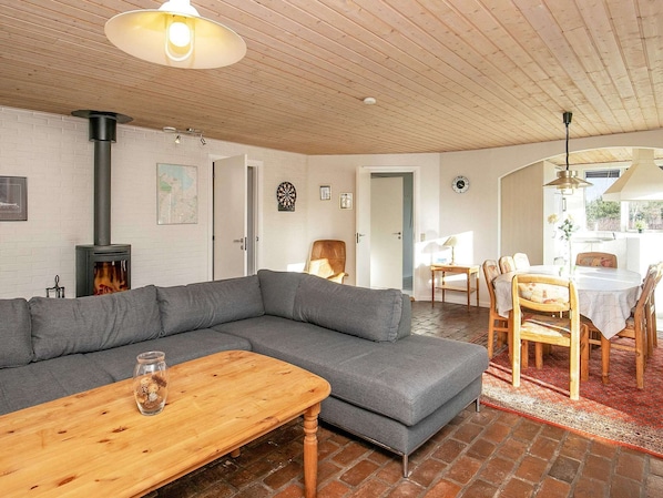 A cozy living room with a sectional sofa, a wooden table, a fireplace, and a dining area with chairs and a table.