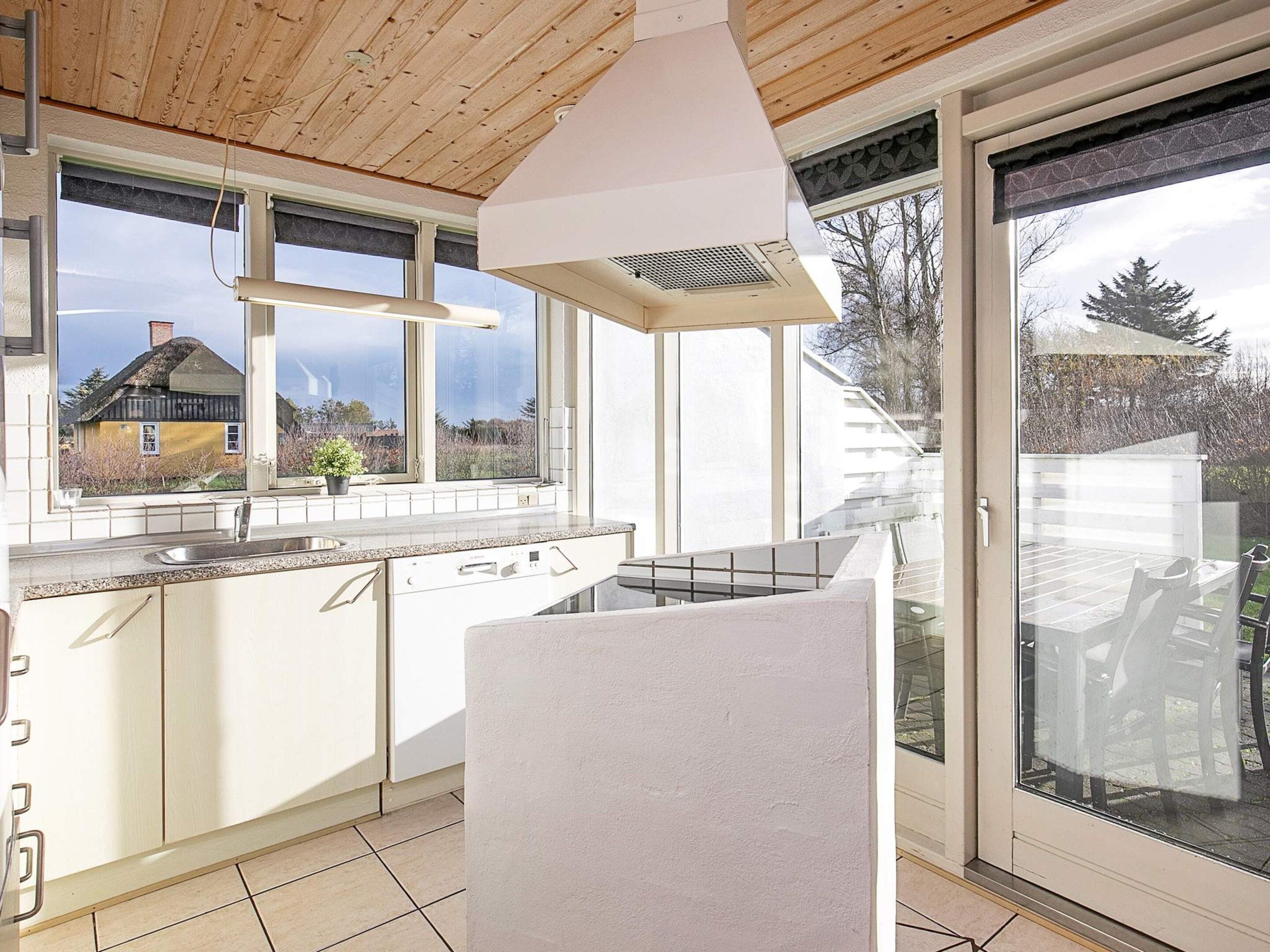 A modern kitchen with a large window, a built-in oven, and a sliding glass door leading to a balcony.