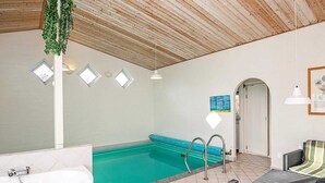 Area piscina con vasca idromassaggio, lettini e soffitto con travi in legno.