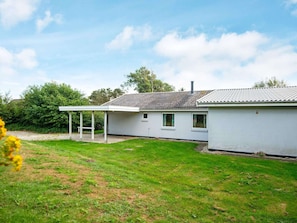 A single-story house with a covered patio, a fenced yard, and a clear sky.