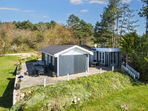 A two-story house with a covered patio and a fenced yard. - 4 Star Holiday Home in Ebeltoft (Ebeltoft)