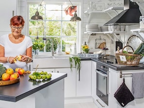 A kitchen with a person peeling an apple, a counter with fruits, and a sign labeled 'COLD DRINKS'. - Holiday Home in Bodafors (Bodafors)