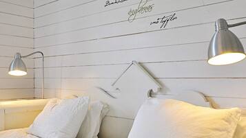 Ein Schlafzimmer mit zwei Betten, weißer Bettwäsche und Wandlampen.