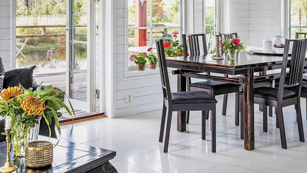 Een eetgedeelte met een tafel voor vier personen, omringd door stoelen, met uitzicht op een tuin door grote ramen.