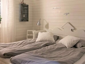 A bedroom with two beds, a bedside table, a lamp, and a wall-mounted shelf. - Holiday Home in Bodafors (Bodafors)