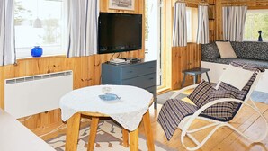 A cozy cabin interior with a television, a dining table, a rocking chair, and a sofa. - 4 Person Holiday Home in Vetlanda (Vetlanda)