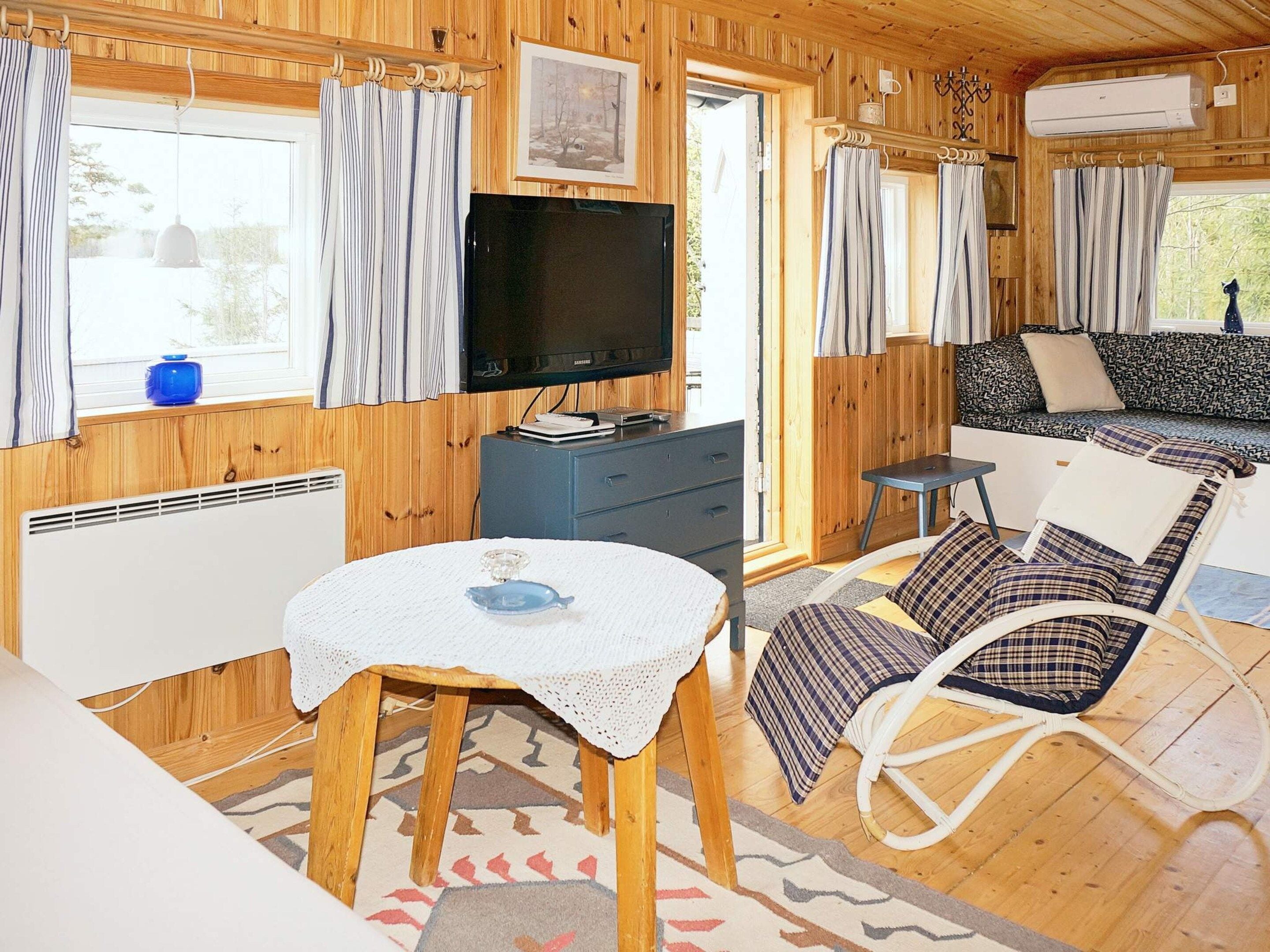 A cozy cabin interior with a television, a dining table, a rocking chair, and a sofa.