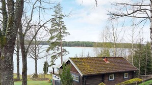 A rustic cabin with a moss-covered roof, surrounded by trees and a lake. - 4 Person Holiday Home in Vetlanda (Vetlanda)