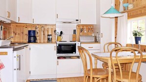 A compact kitchen with white cabinets, a microwave, a coffee maker, and a dining table with chairs. - 4 Person Holiday Home in Vetlanda (Vetlanda)