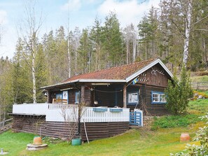 A wooden cabin with a porch, surrounded by trees. - 4 Person Holiday Home in Vetlanda (Vetlanda)