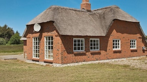 Une maison en briques avec un toit de chaume et une cheminée.