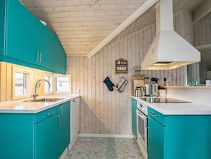 Une cuisine avec des armoires de couleur turquoise, un évier blanc et un plafond en bois.