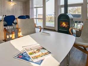 Una habitación con una mesa blanca, sillas azules, una chimenea y vistas al exterior.