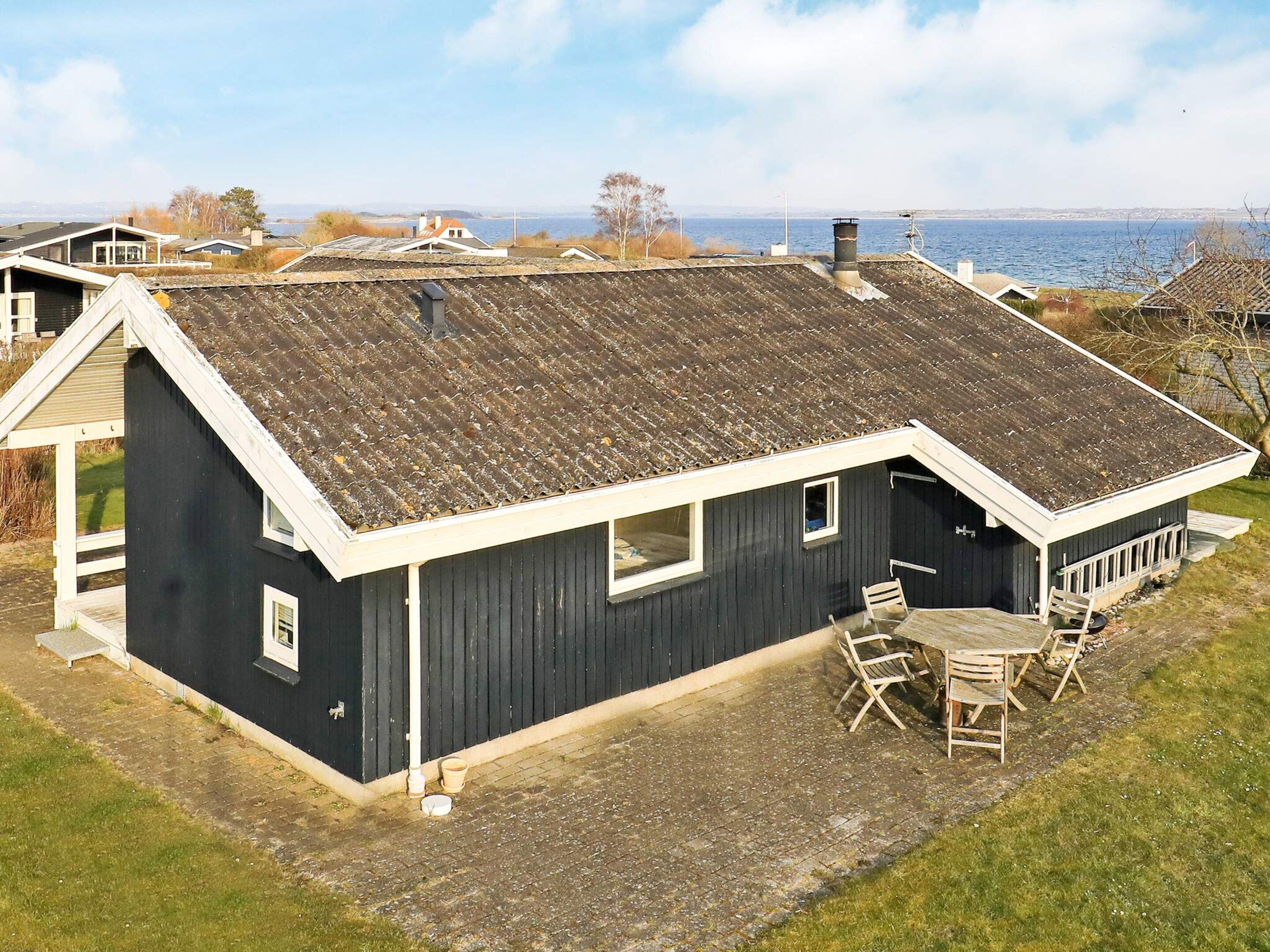 A single-story house with a dark exterior, a sloped roof, and a small patio with a table and chairs.