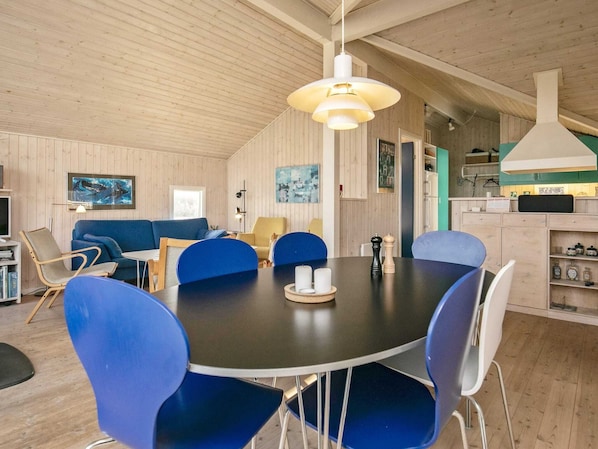 Un coin repas avec une table ronde, des chaises bleues et un luminaire suspendu.