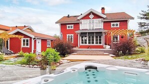 A two-story red house with a hot tub in the foreground. - Holiday Home in Vaxholm (Vaxholm)