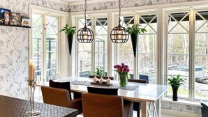 A dining area with a table set for four, surrounded by chairs, with hanging plants and pendant lights. - Holiday Home in Vaxholm (Vaxholm)