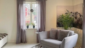 A living room with a grey sofa, a patterned rug, and a window with curtains. - Holiday Home in Vaxholm (Vaxholm)