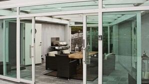 A modern outdoor dining area with a grill, seating, and glass doors. - Holiday Home in Inndyr (Gildeskal)