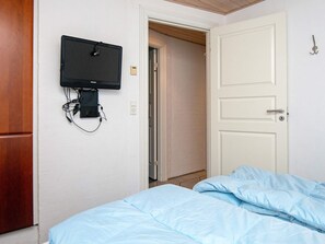 A bedroom with a bed, a television mounted on the wall, and a door leading to another room. - 5 Star Holiday Home in Ulfborg (Ulfborg)