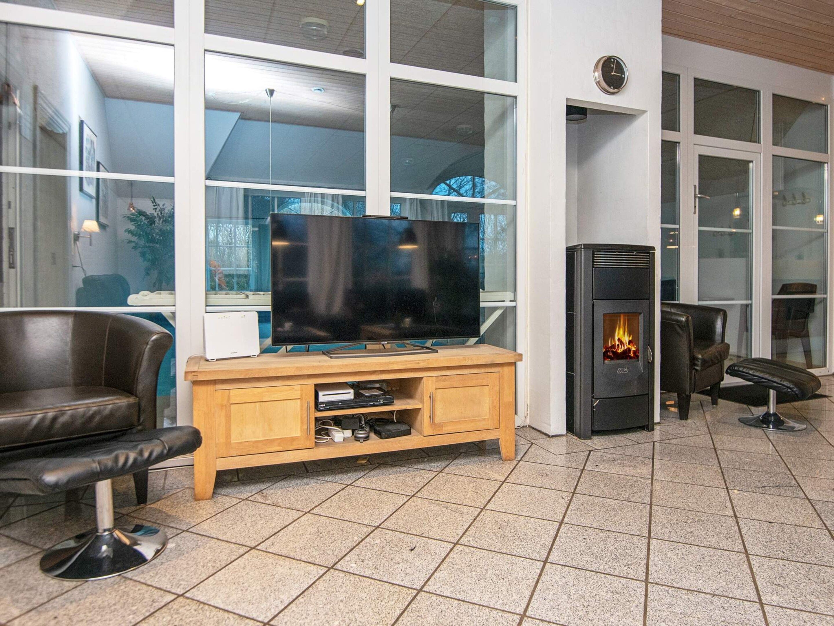 A modern living room with a flat-screen TV on a wooden stand, a fireplace, and a leather sofa.