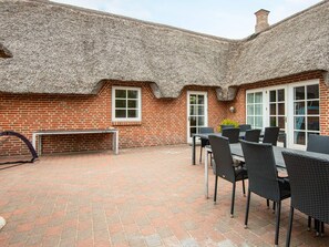 A brick patio with a thatched roof, a table with chairs, and a bench. - 5 Star Holiday Home in Ulfborg (Ulfborg)