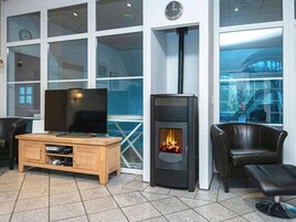 Una sala de estar moderna con un televisor grande, un mueble de madera, una chimenea negra y asientos de cuero.